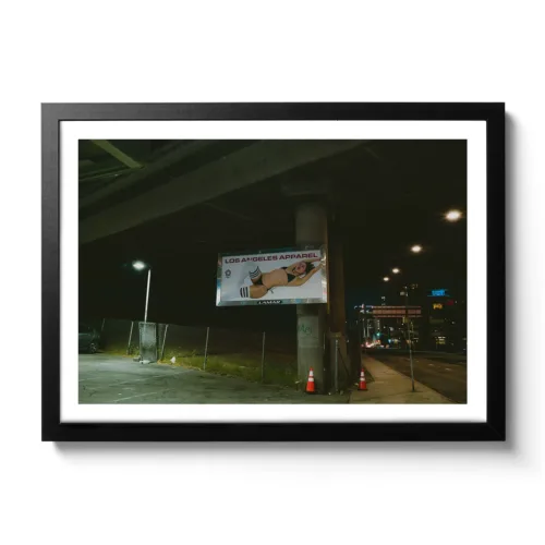 Bildaufnahme bei Nacht von einer Werbetafel das eine freizügige Dame in Unterwäsche zeigt