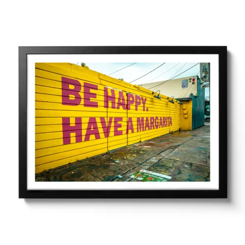 Picture of a yellow wall with the lettering "Be Happy Have a Margarita"