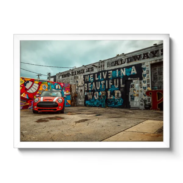 Image of a car repair shop painted with graffiti and a red Mini parked in front of it.
