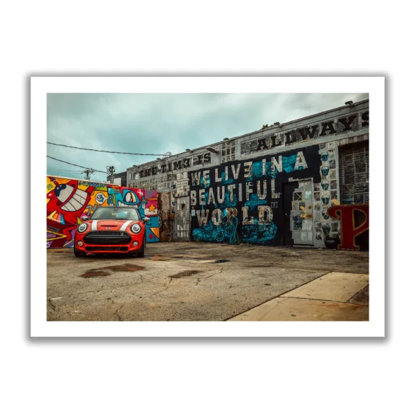 Image of a car repair shop painted with graffiti and a red Mini parked in front of it.