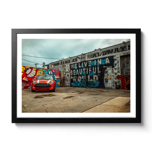 Image of a car repair shop painted with graffiti and a red Mini parked in front of it.