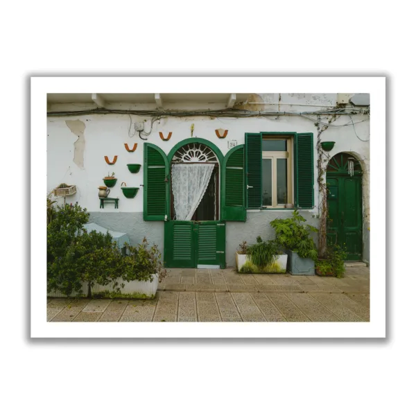 Image of a small Italian house wall with green shutters.