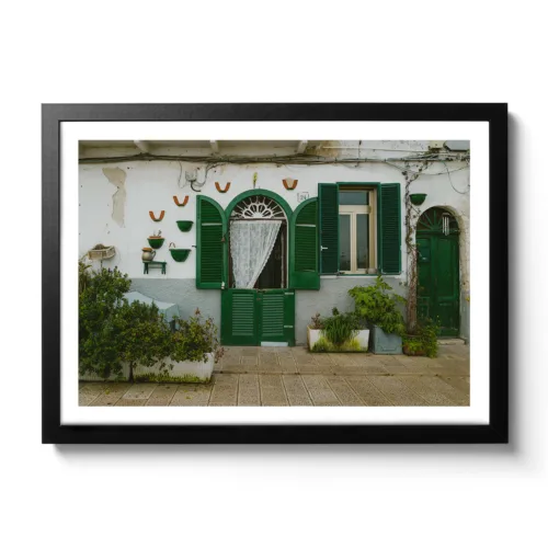 Bildaufnahme einer kleinen italienischen Hausmauer mit grünen Fensterläden.