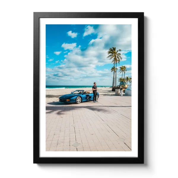Young man stands in front of a blue Ferrari on the beach in Fort Lauderdale.