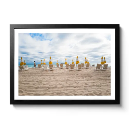 Bildaufnahme von einem leeren Strand, wo alle gelben Schirme zugespannt sind.