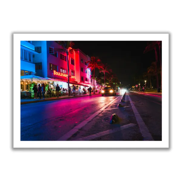 Image of Ocean Drive in Miami at night. Neon lights and a moving car.