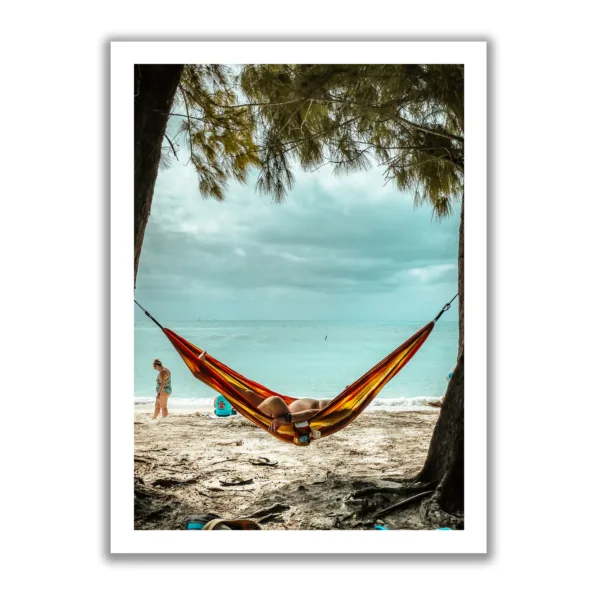 Bildaufnahme eines Mannes, der am Strand unter Palmen in einer Hängematte liegt und das Meer im Hintergrund ist. Das lustige dabei, man sieht sein kleines Bäuchlein.